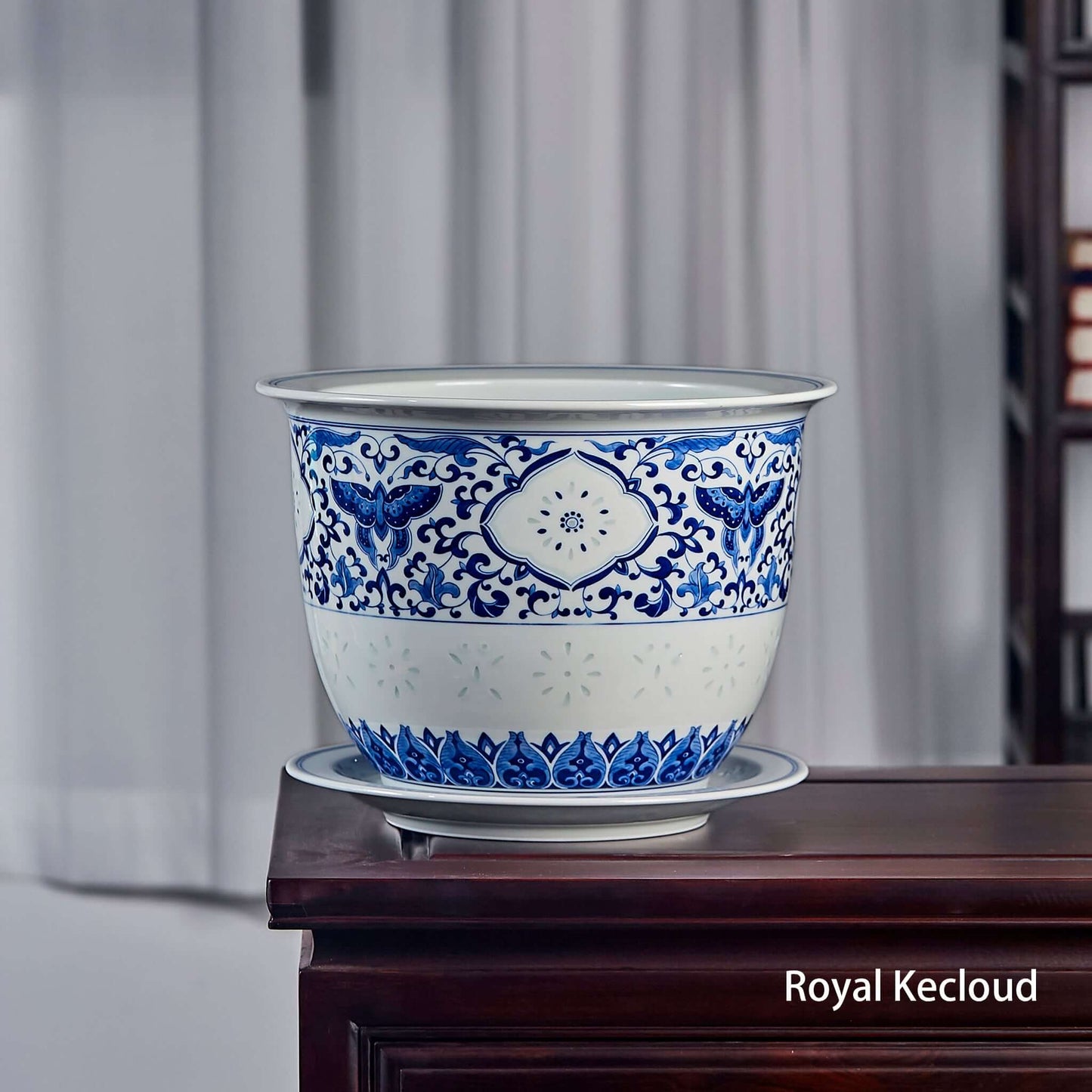Blue and White Porcelain Jardinière featuring butterfly and floral designs, elegantly displayed on a wooden table.