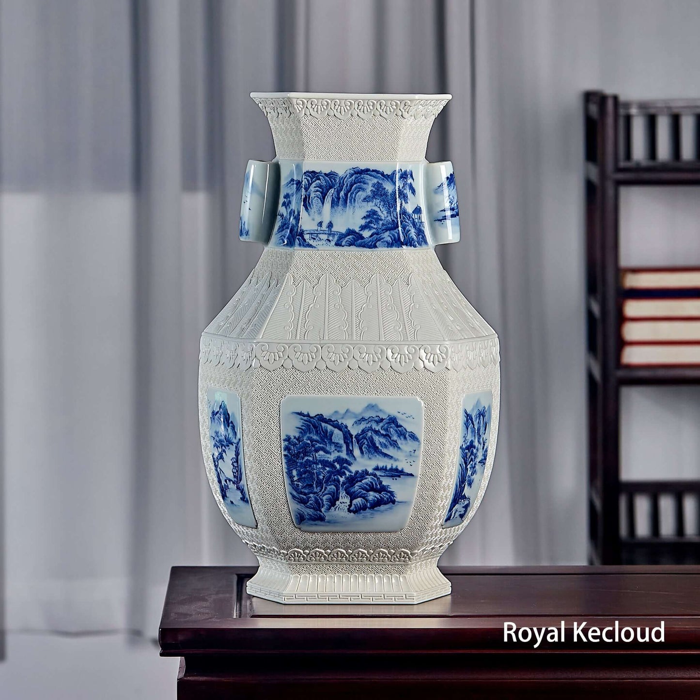 Blue and White Ceramic Vase with carved landscape design featuring handles and elegant hexagonal shape.